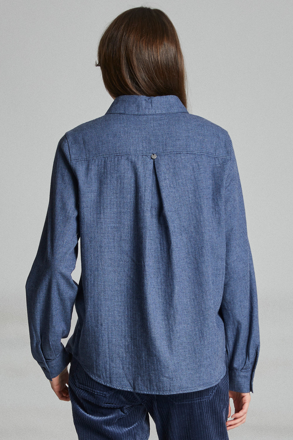 Person wearing a blue denim shirt against a gray background