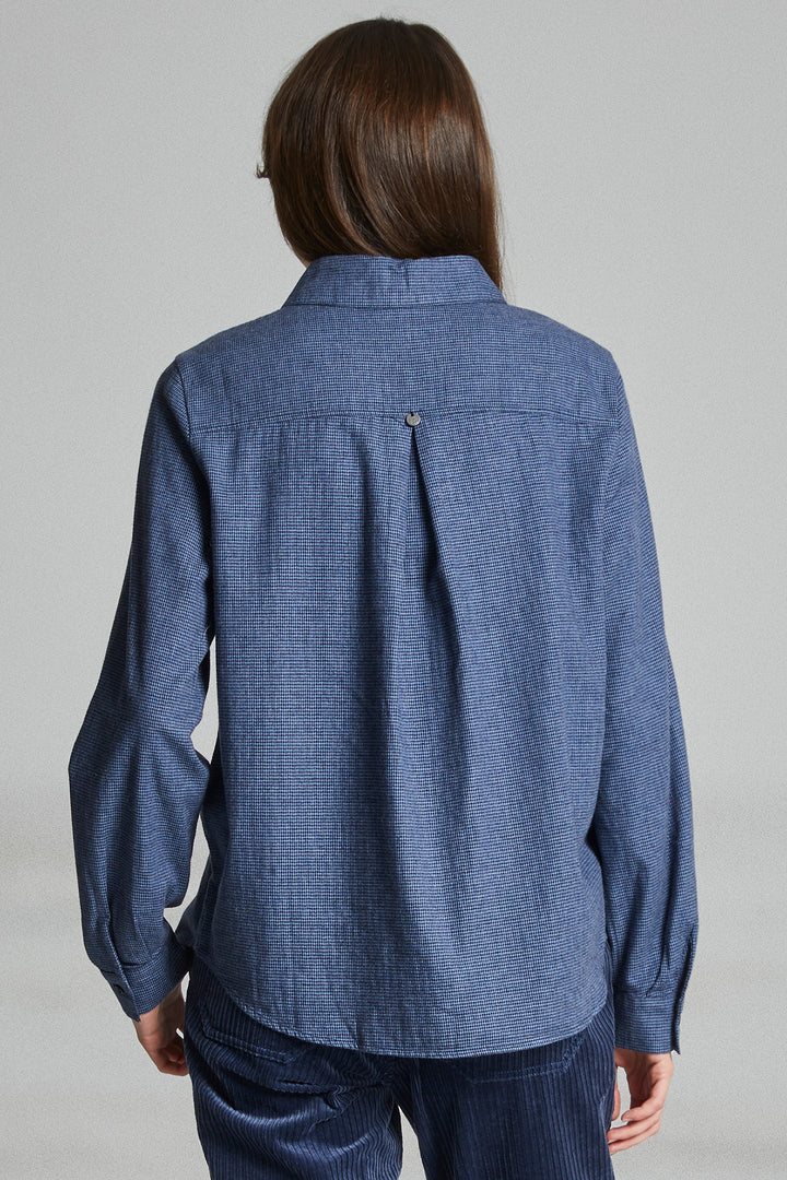 Person wearing a blue denim shirt against a gray background