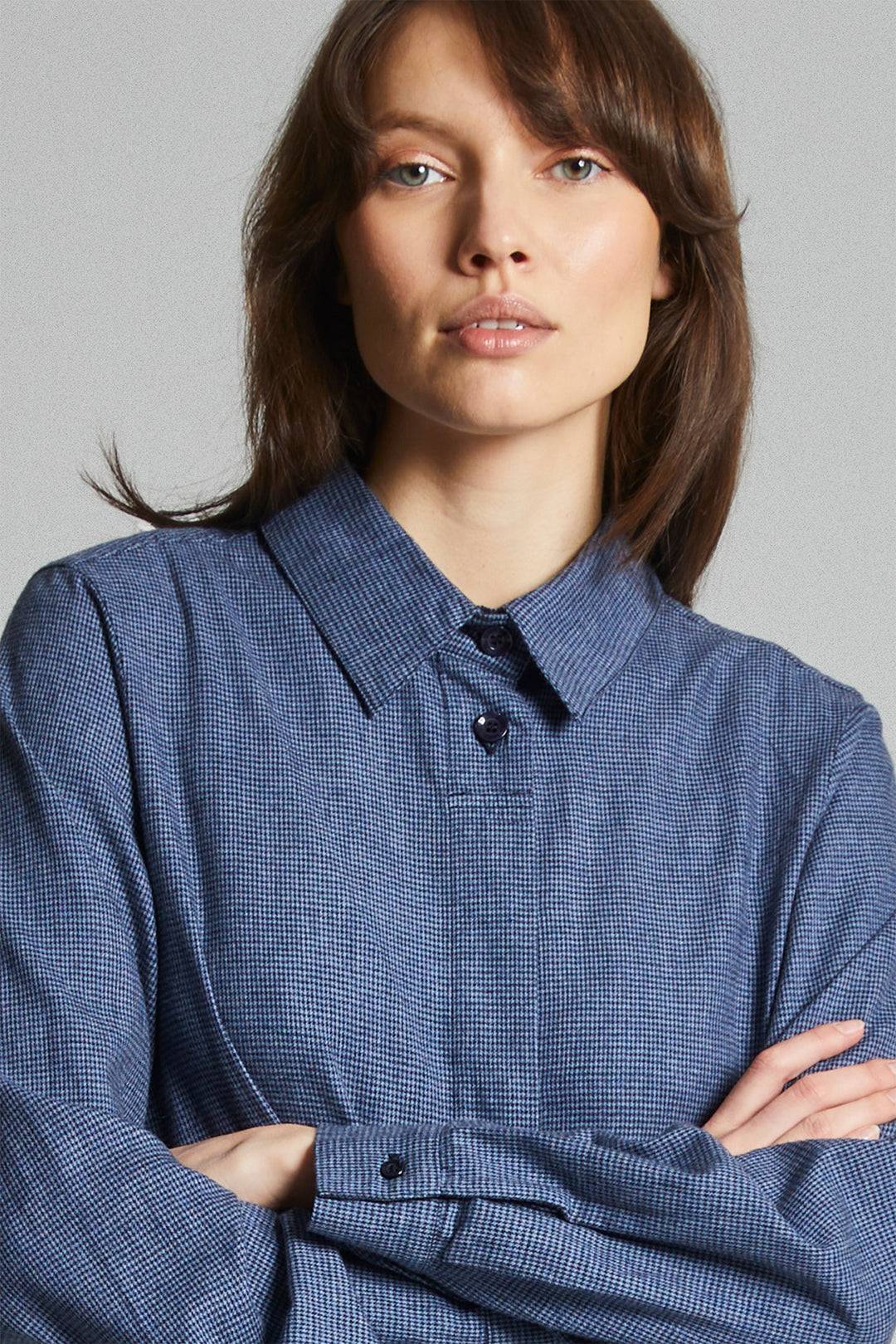 Woman wearing a blue checkered shirt against a gray background