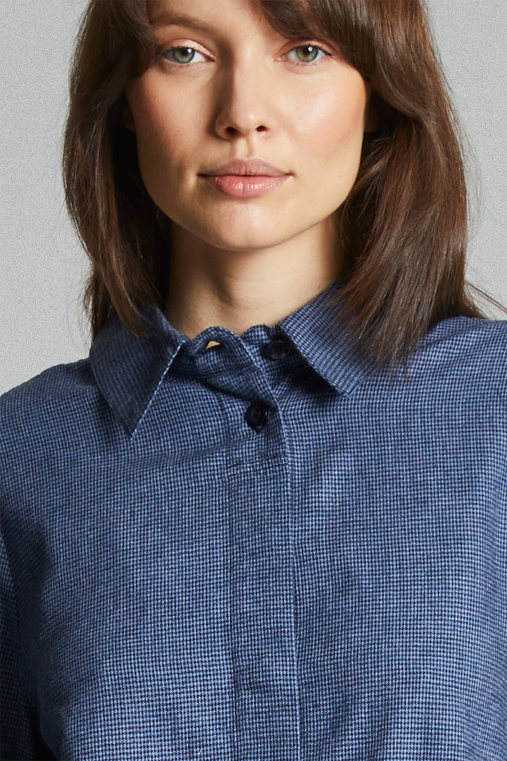 Person wearing a blue checkered shirt against a gray background