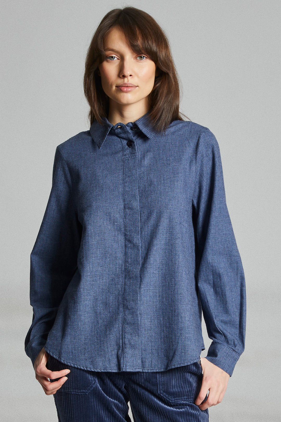 Woman wearing a blue shirt against a gray background