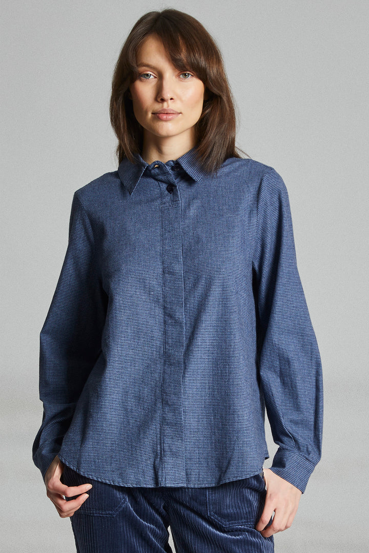Woman wearing a blue shirt against a gray background