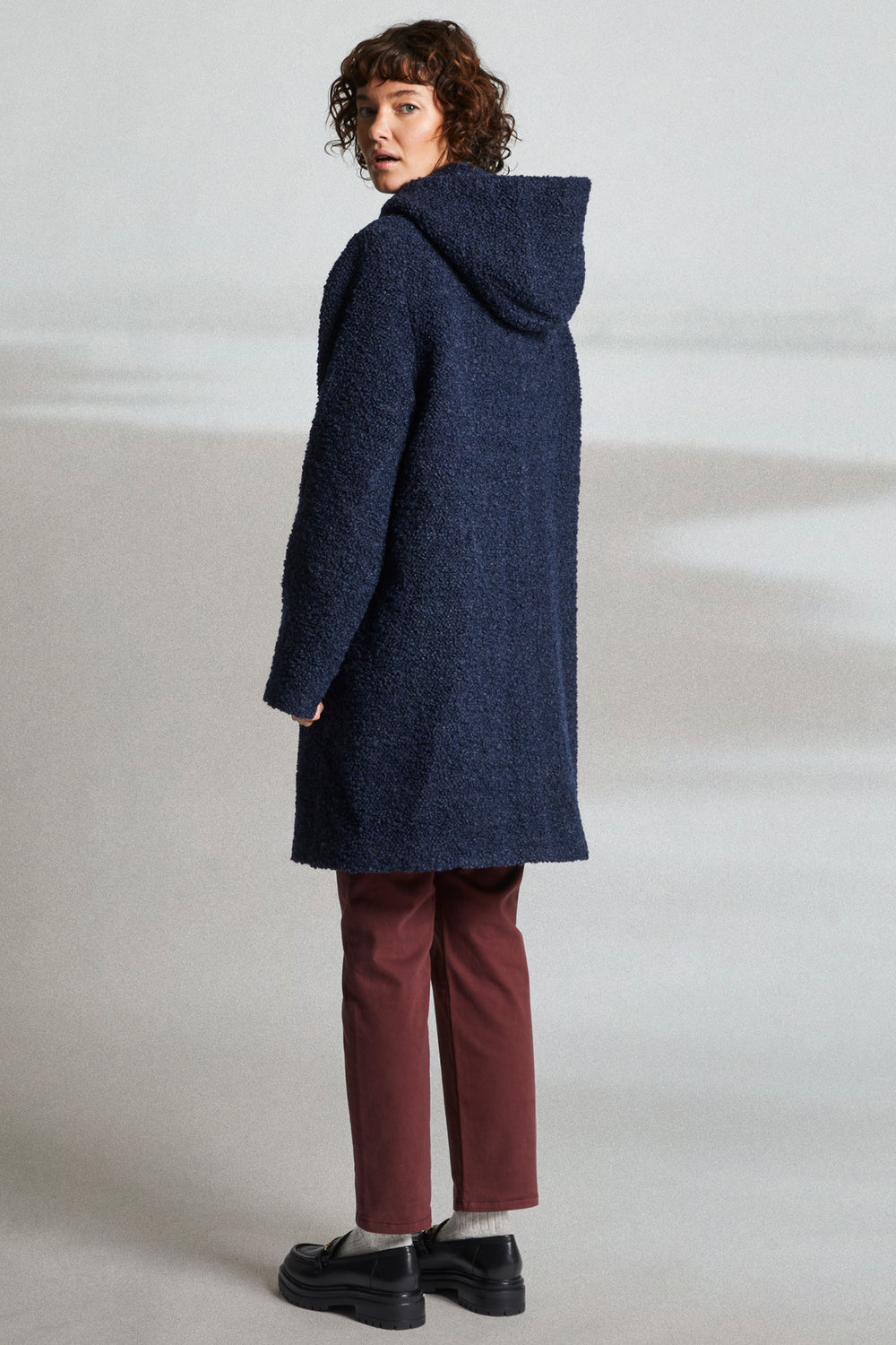 Person wearing a blue hooded coat on a plain background