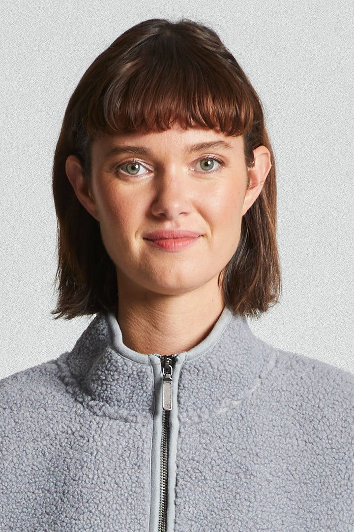 Person wearing a gray fleece jacket with a plain background