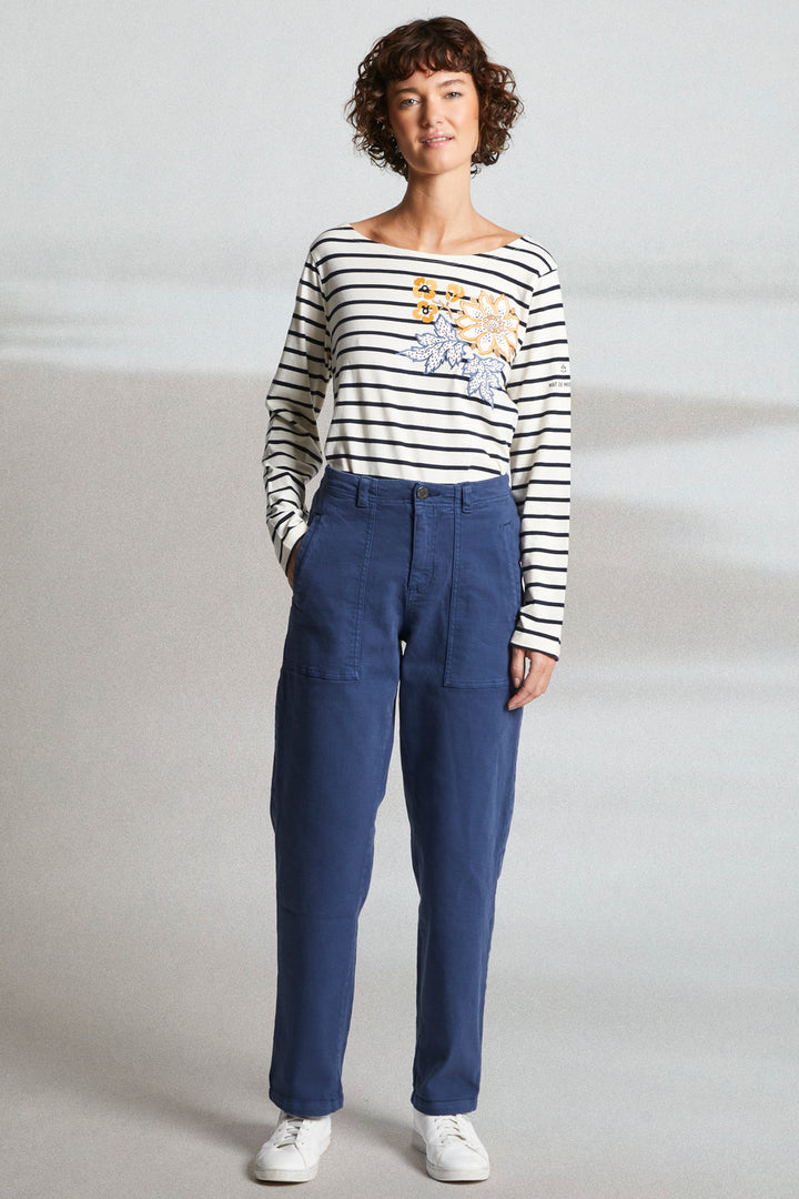Woman wearing a striped shirt and blue pants on a plain background