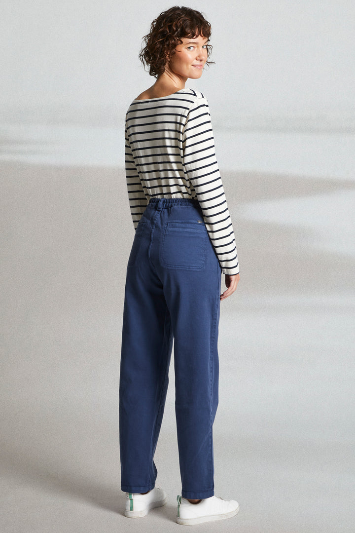 Person wearing a striped shirt and blue pants on a plain background