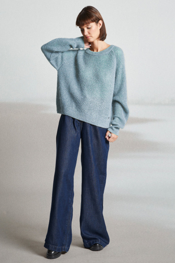 Person wearing a light blue sweater and dark blue pants on a plain background