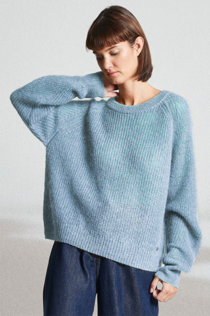 Woman wearing a light blue sweater against a plain background