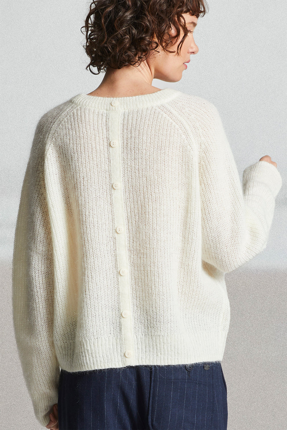 Person wearing a cream-colored cardigan against a plain background