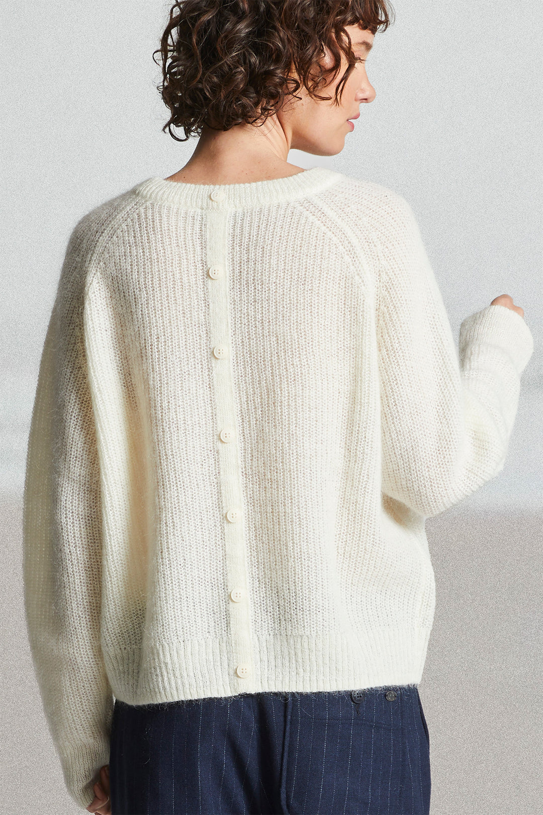 Person wearing a cream-colored cardigan against a plain background