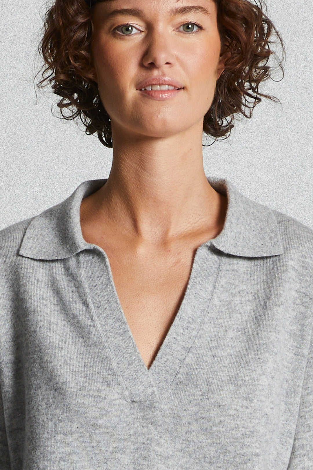 Woman wearing a gray polo shirt against a light background