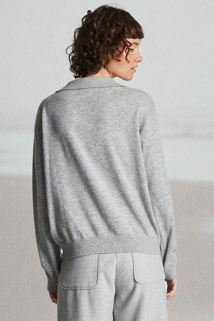 Person wearing a gray sweater and light gray pants against a plain background