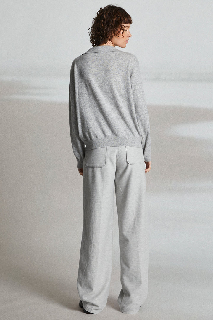 Person wearing a gray sweater and pants on a white background