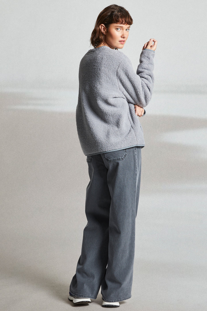 Person wearing a gray sweater and jeans on a plain background