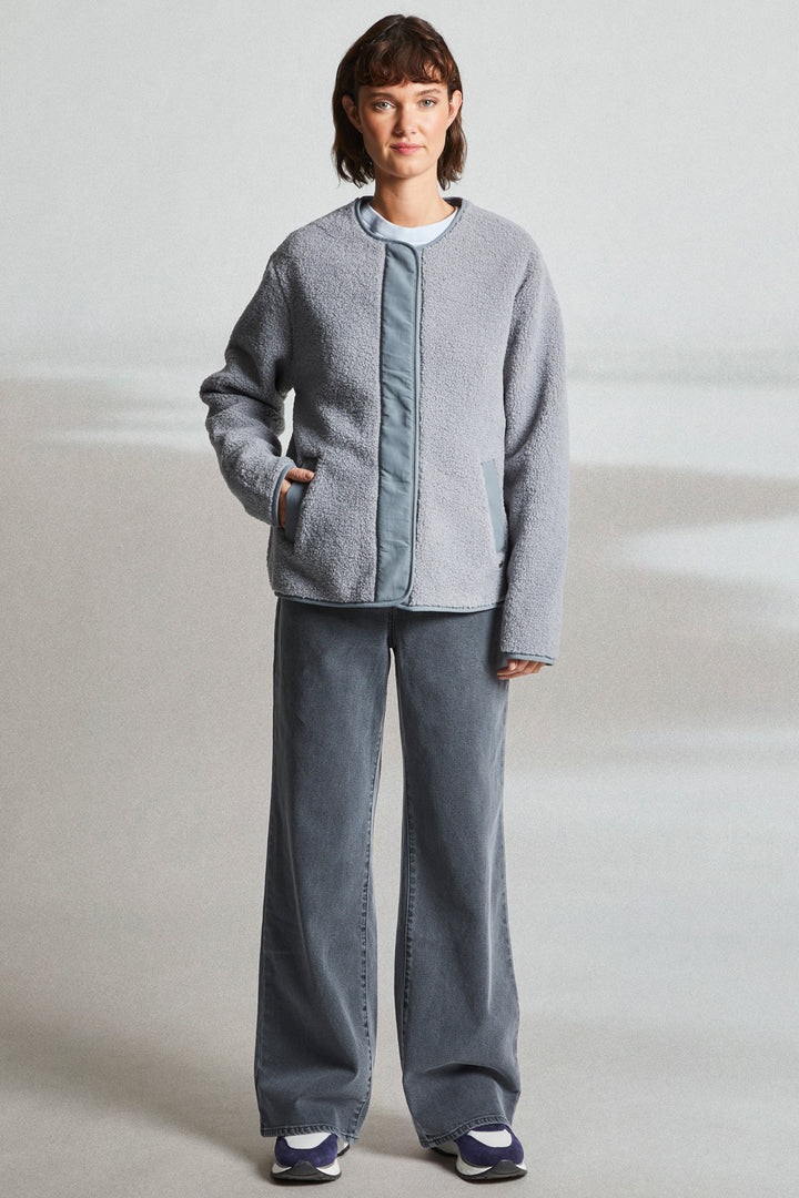 Person wearing a gray jacket and pants on a plain background