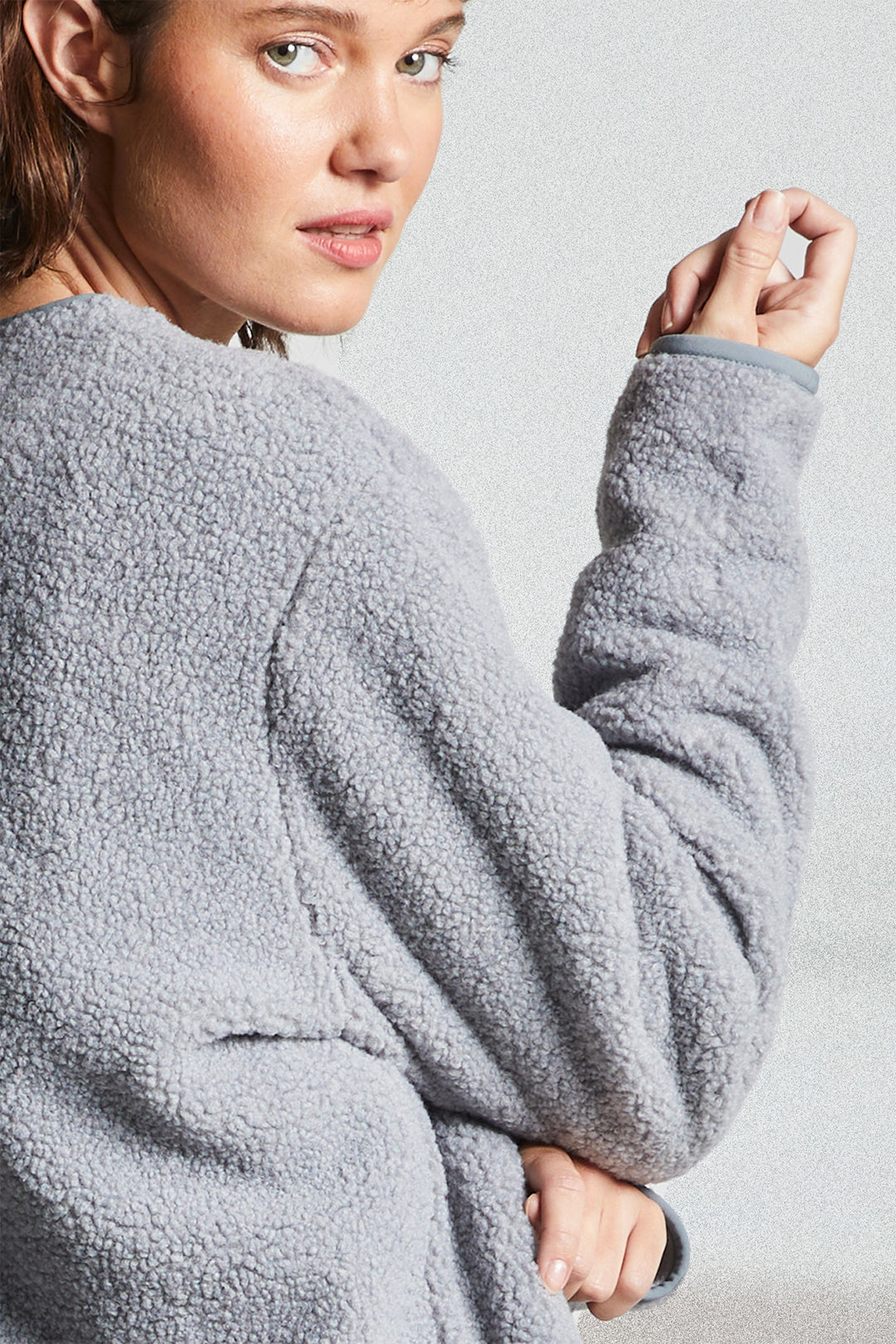 Person wearing a gray fleece jacket against a plain background