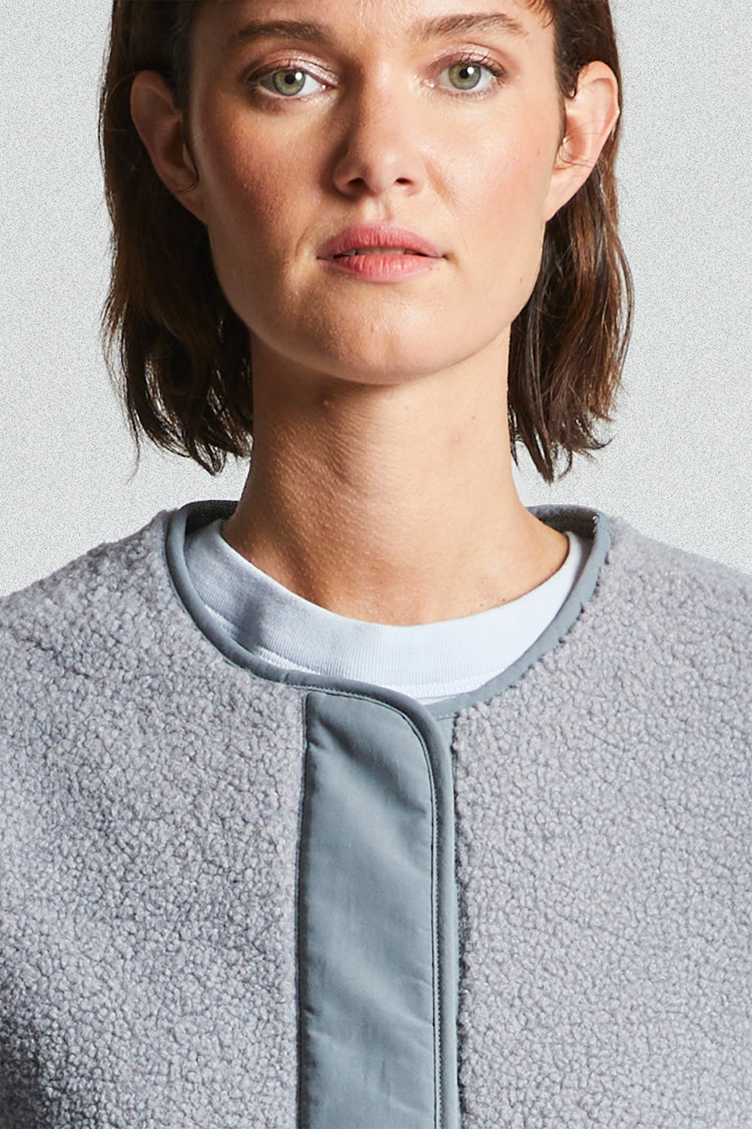 Person wearing a gray fleece jacket against a light gray background