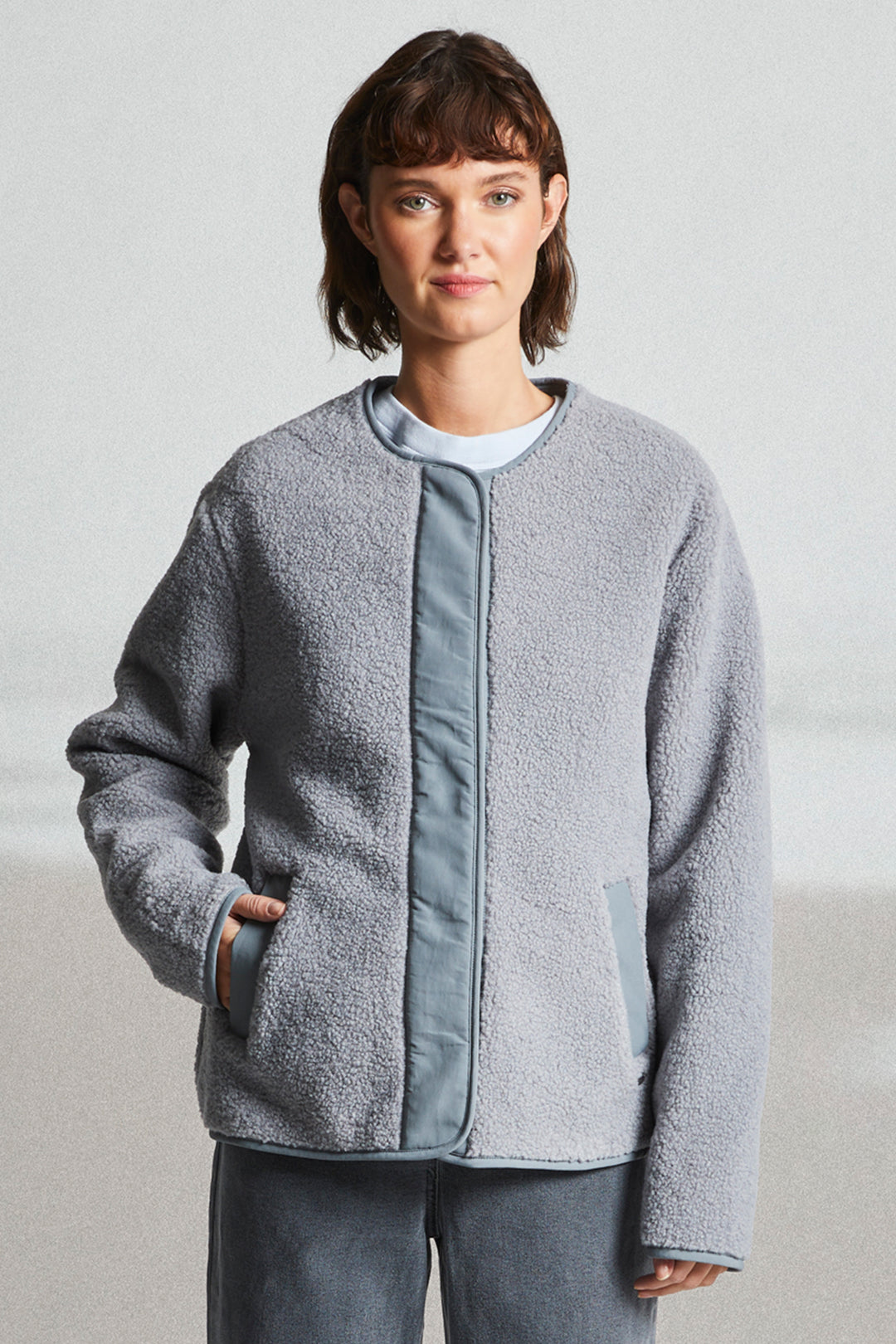Person wearing a gray fleece jacket with a plain background