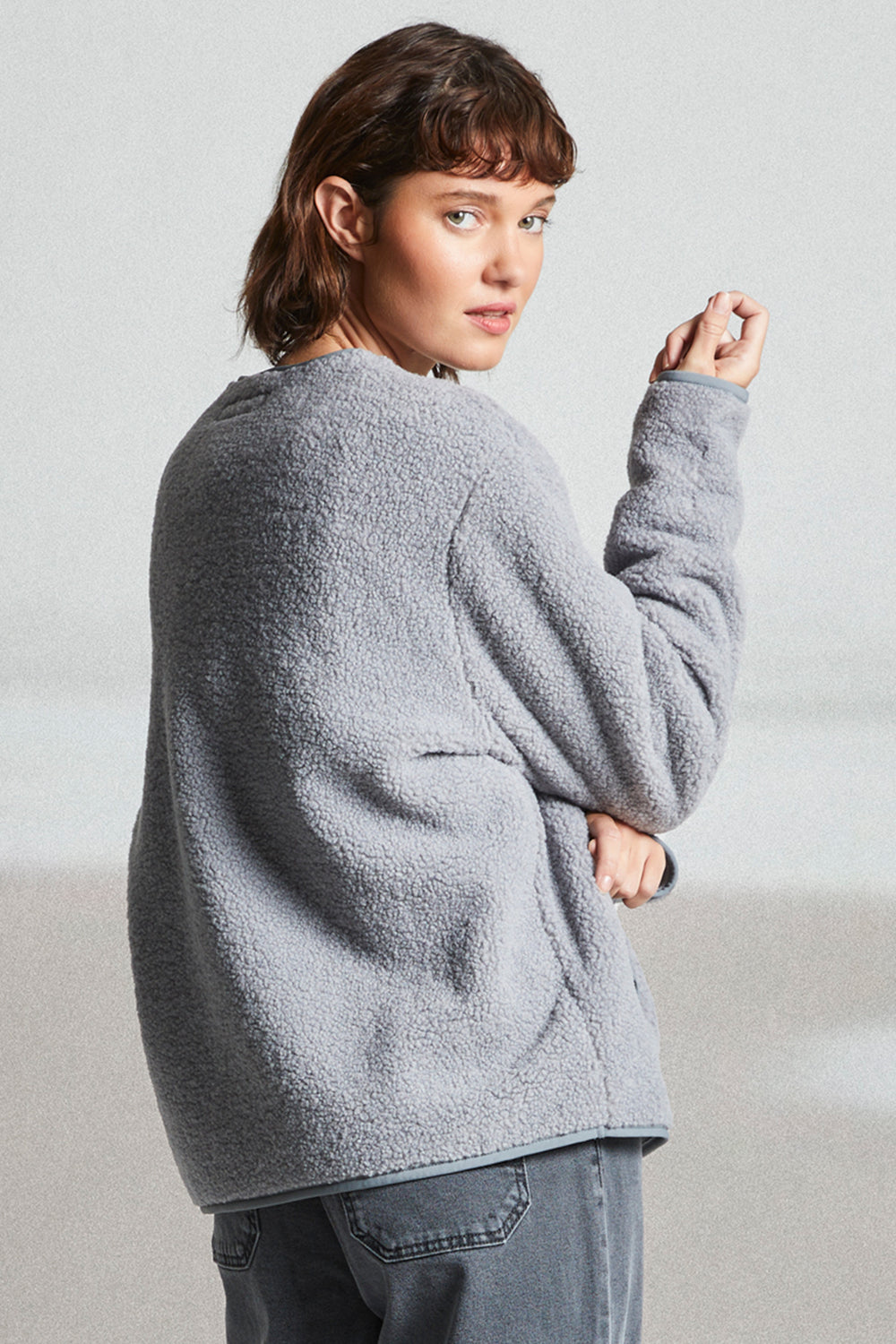 Person wearing a gray fleece jacket against a plain background