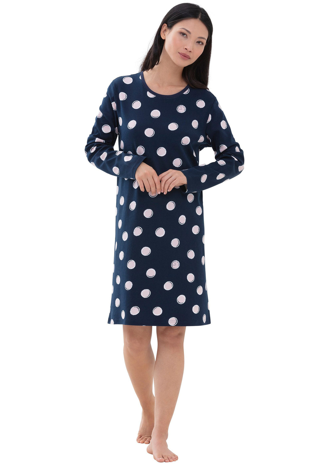 Woman wearing a navy blue nightgown with white polka dots on a white background