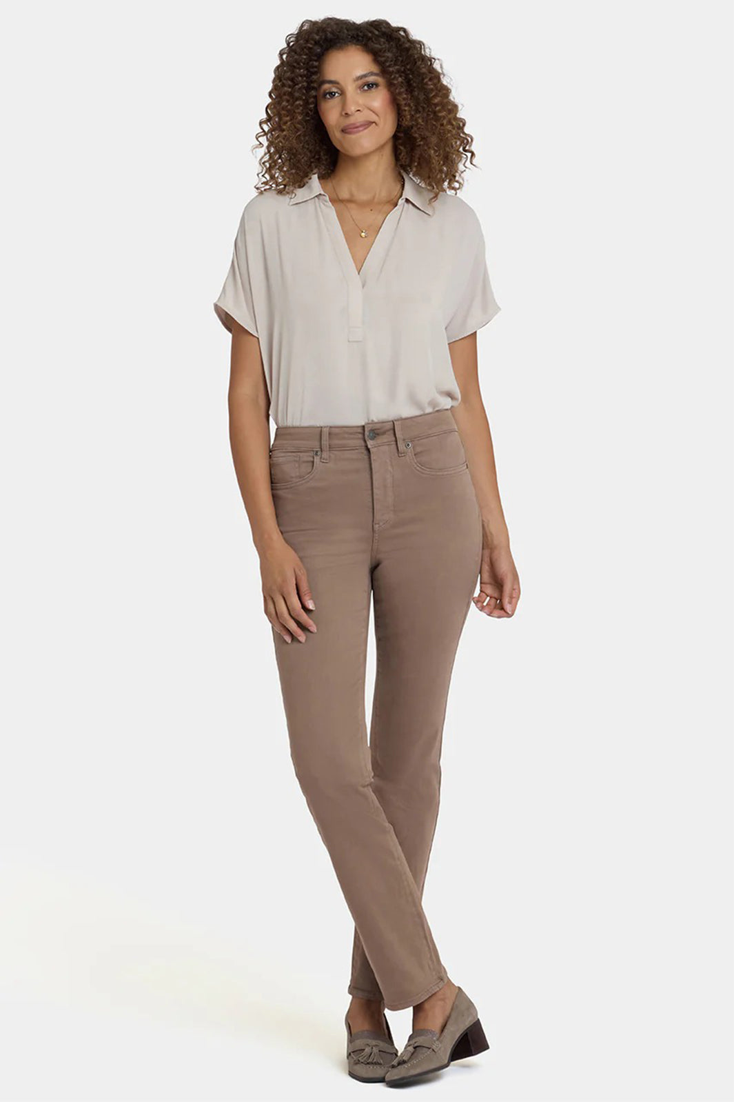 Woman wearing a beige shirt and brown pants on a white background
