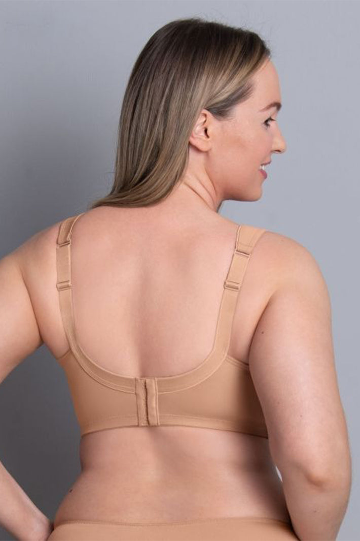Woman wearing a beige bra against a gray background