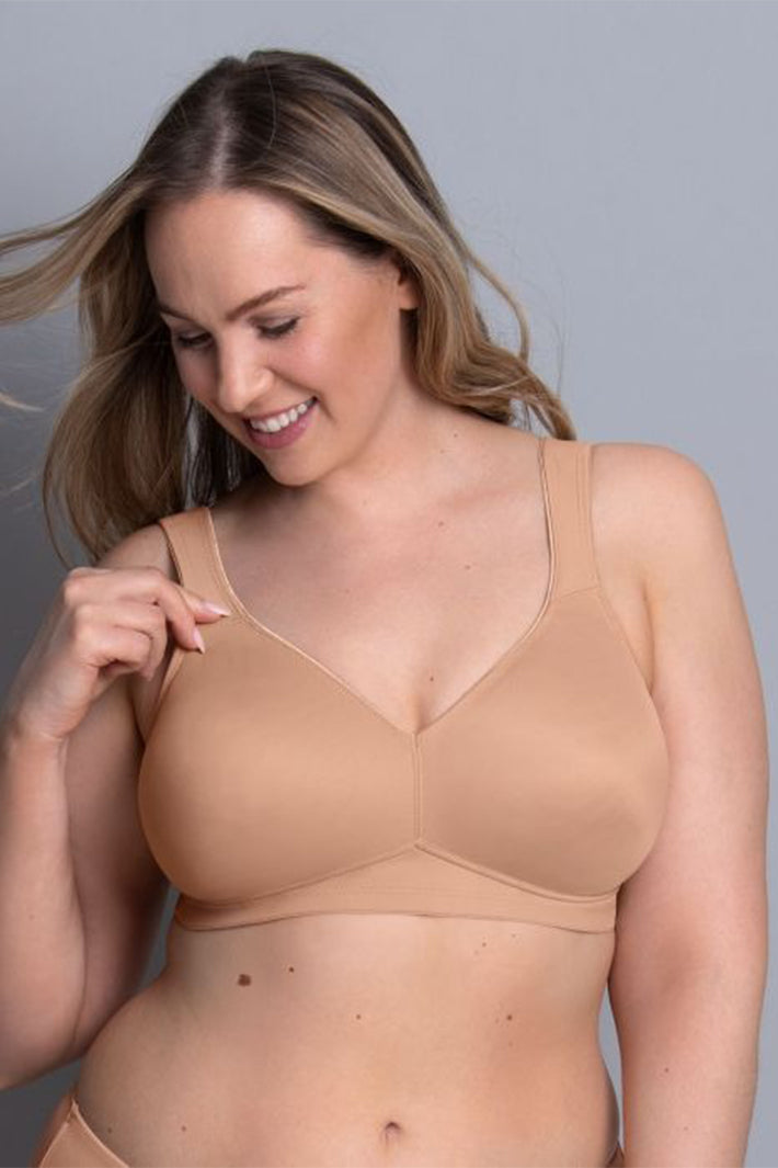 Woman wearing a beige bra against a gray background