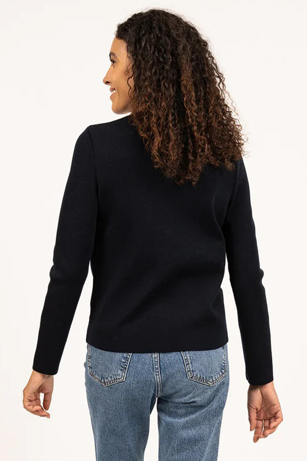 Woman wearing a navy long-sleeve top and blue jeans on a white background