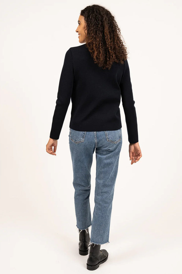 Woman wearing a navy sweater and blue jeans on a white background
