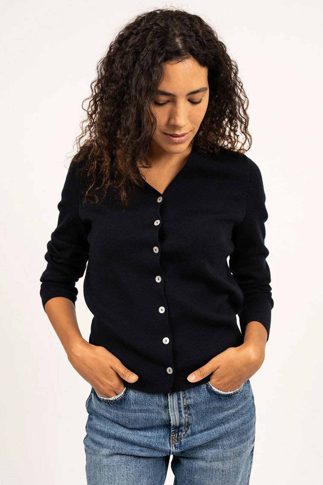 Woman wearing a navy cardigan and blue jeans on a white background