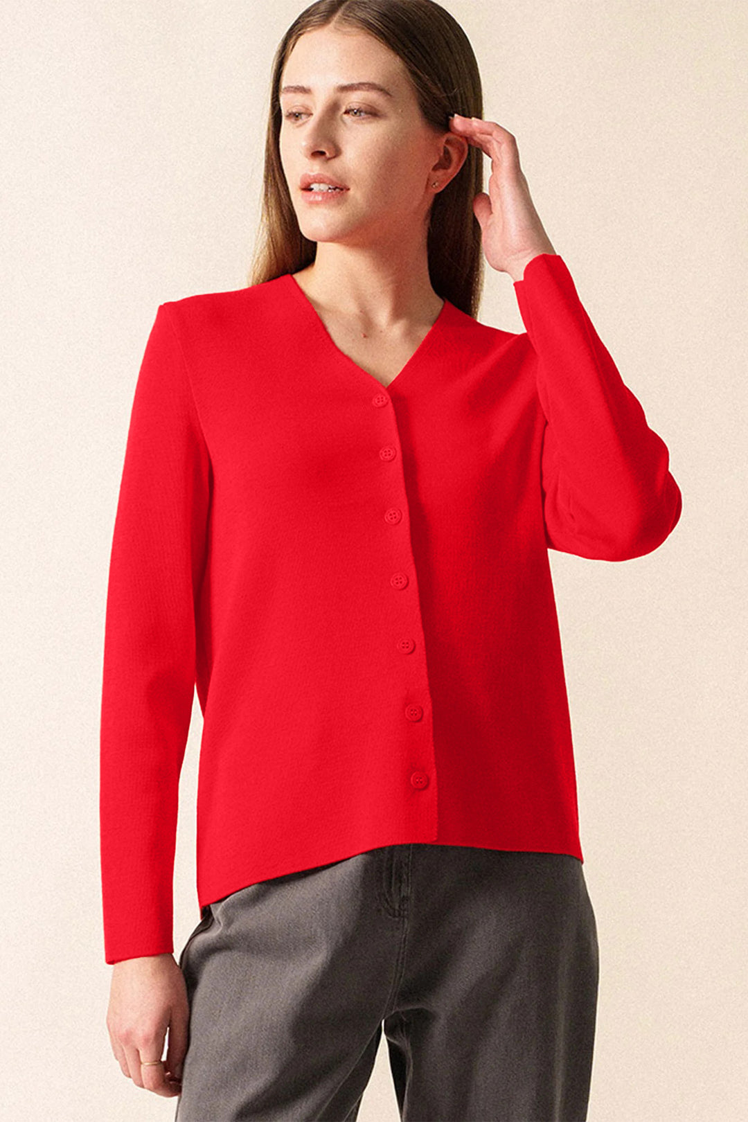 Woman wearing a red cardigan against a beige background
