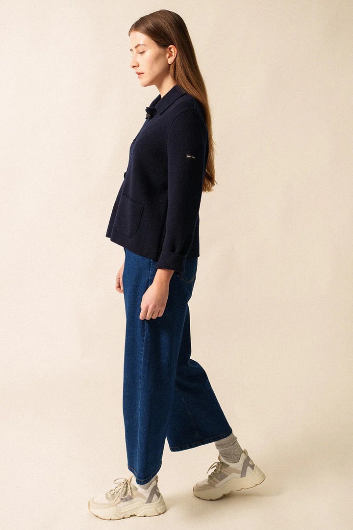 Woman wearing a navy sweater and blue pants on a beige background
