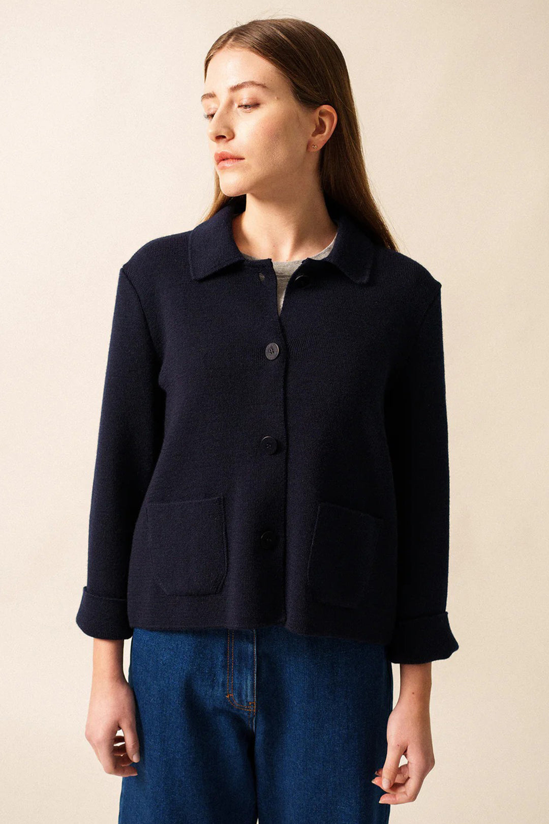 Woman wearing a navy blue jacket against a beige background