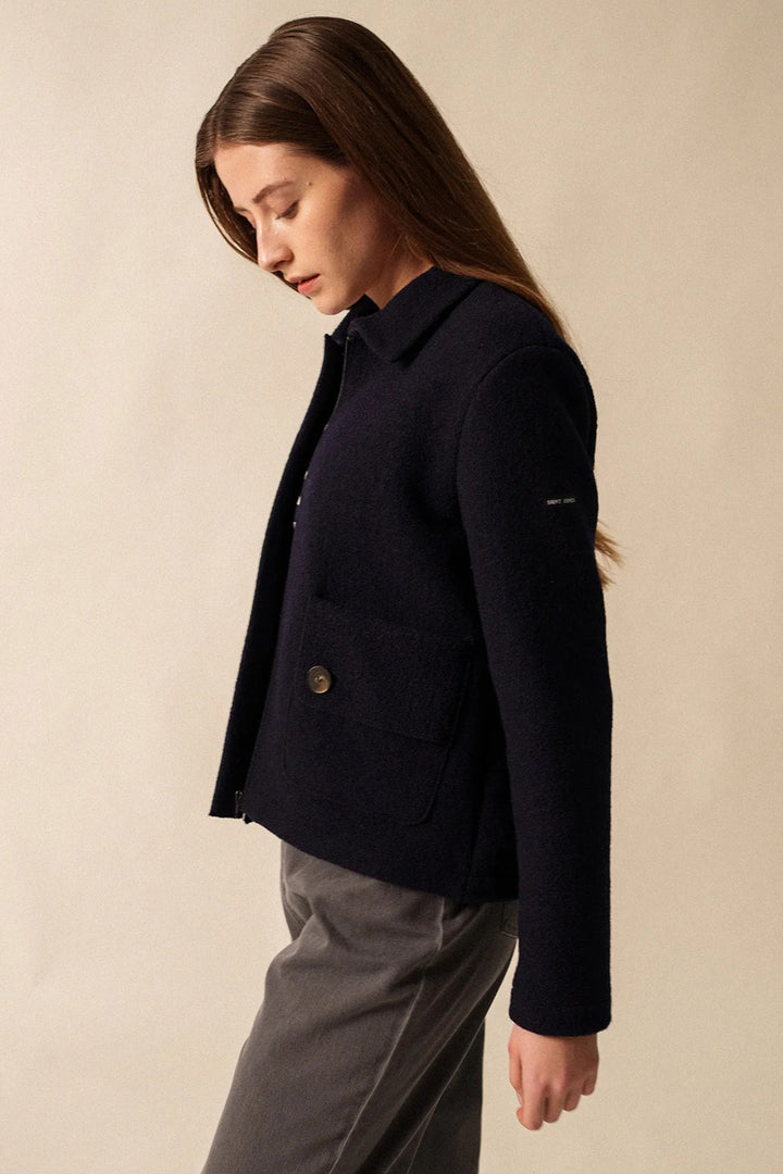 Person wearing a navy blue jacket against a beige background