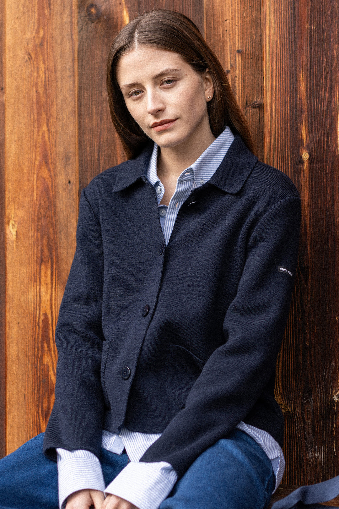 Woman wearing a dark blue coat against a wooden background