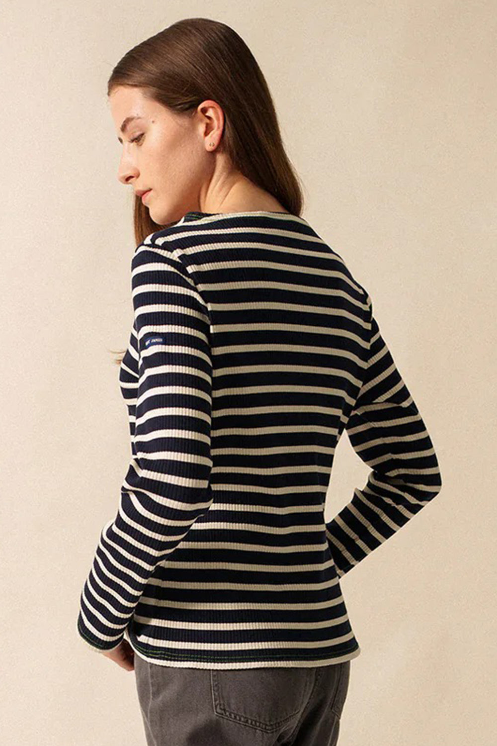 Person wearing a black and white striped long-sleeve shirt against a beige background