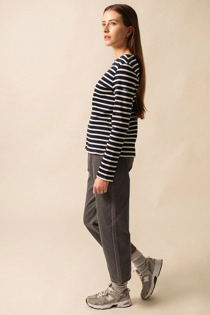 Woman wearing a striped sweater and gray pants on a beige background