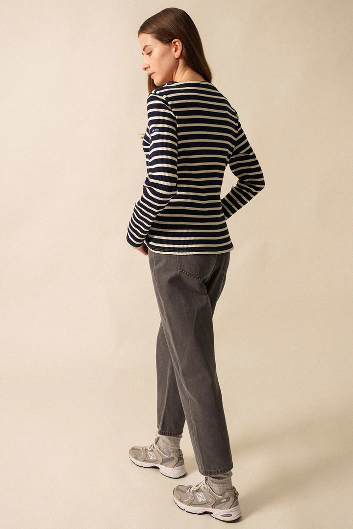 Person wearing a striped sweater and gray pants on a beige background