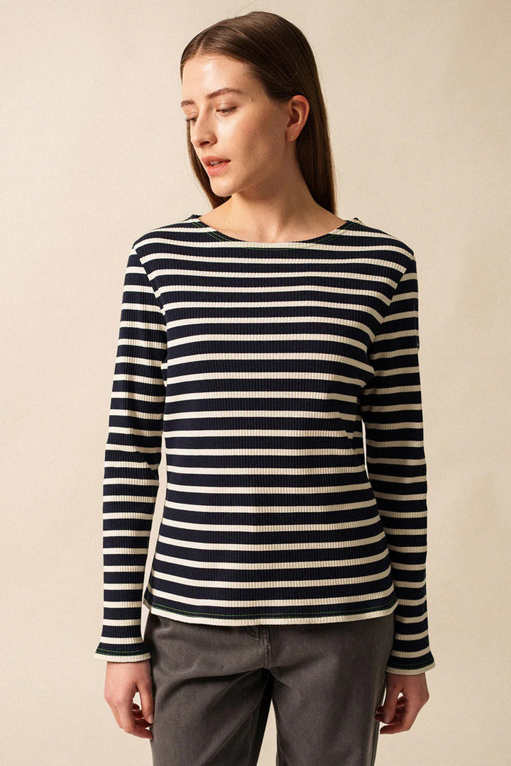 Woman wearing a black and white striped sweater against a beige background