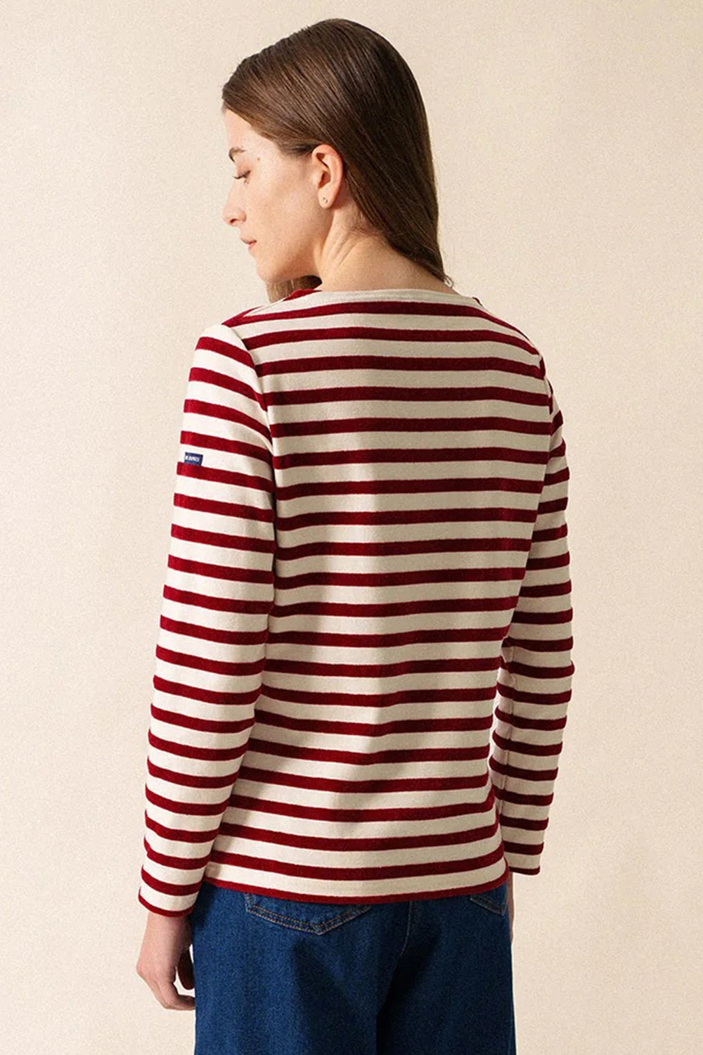 Person wearing a red and white striped sweater against a beige background