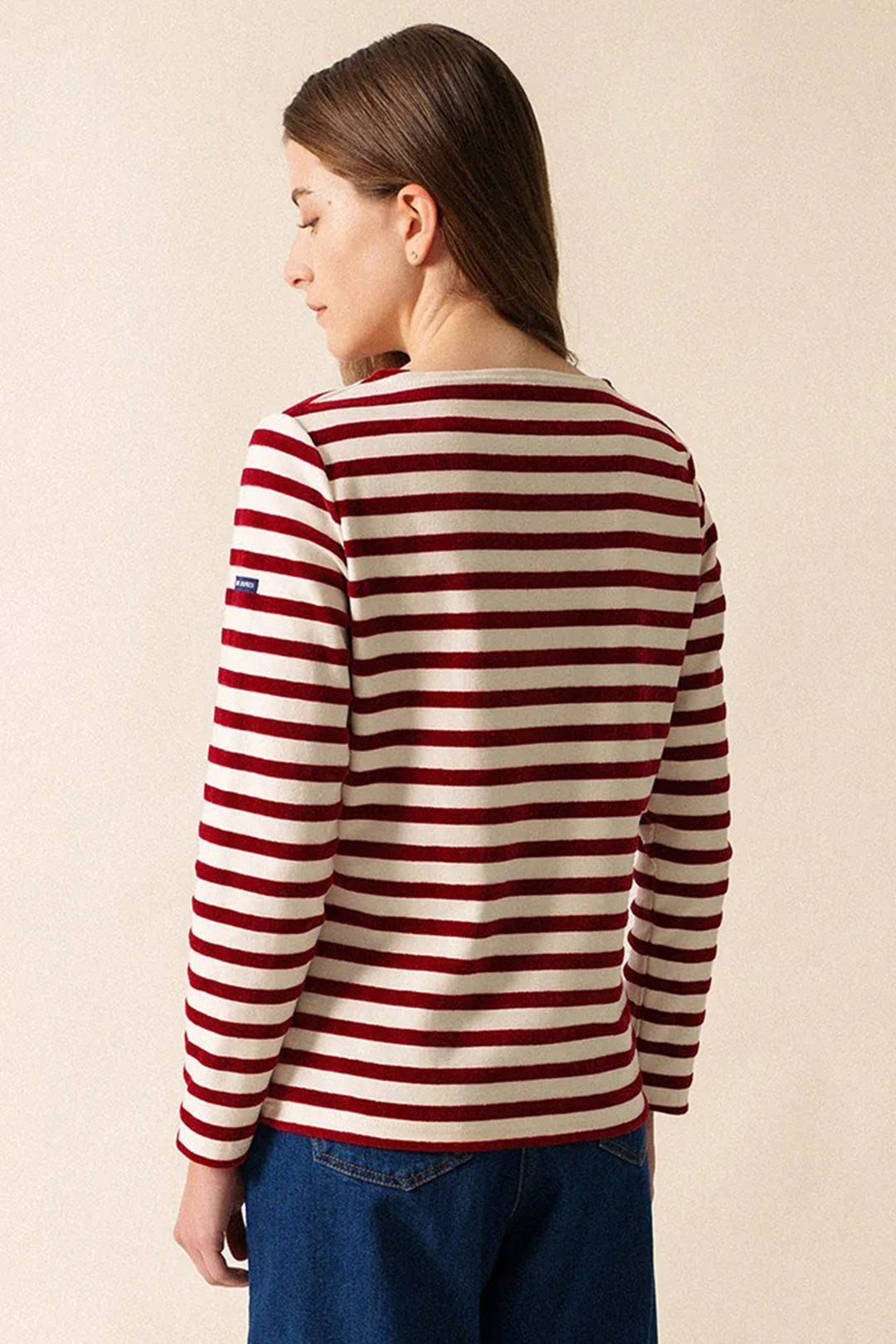 Person wearing a red and white striped sweater against a beige background