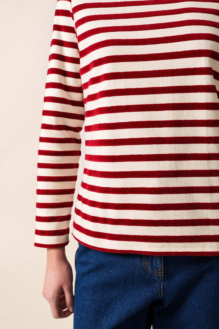 Red and white striped long-sleeve shirt worn by a person against a beige background