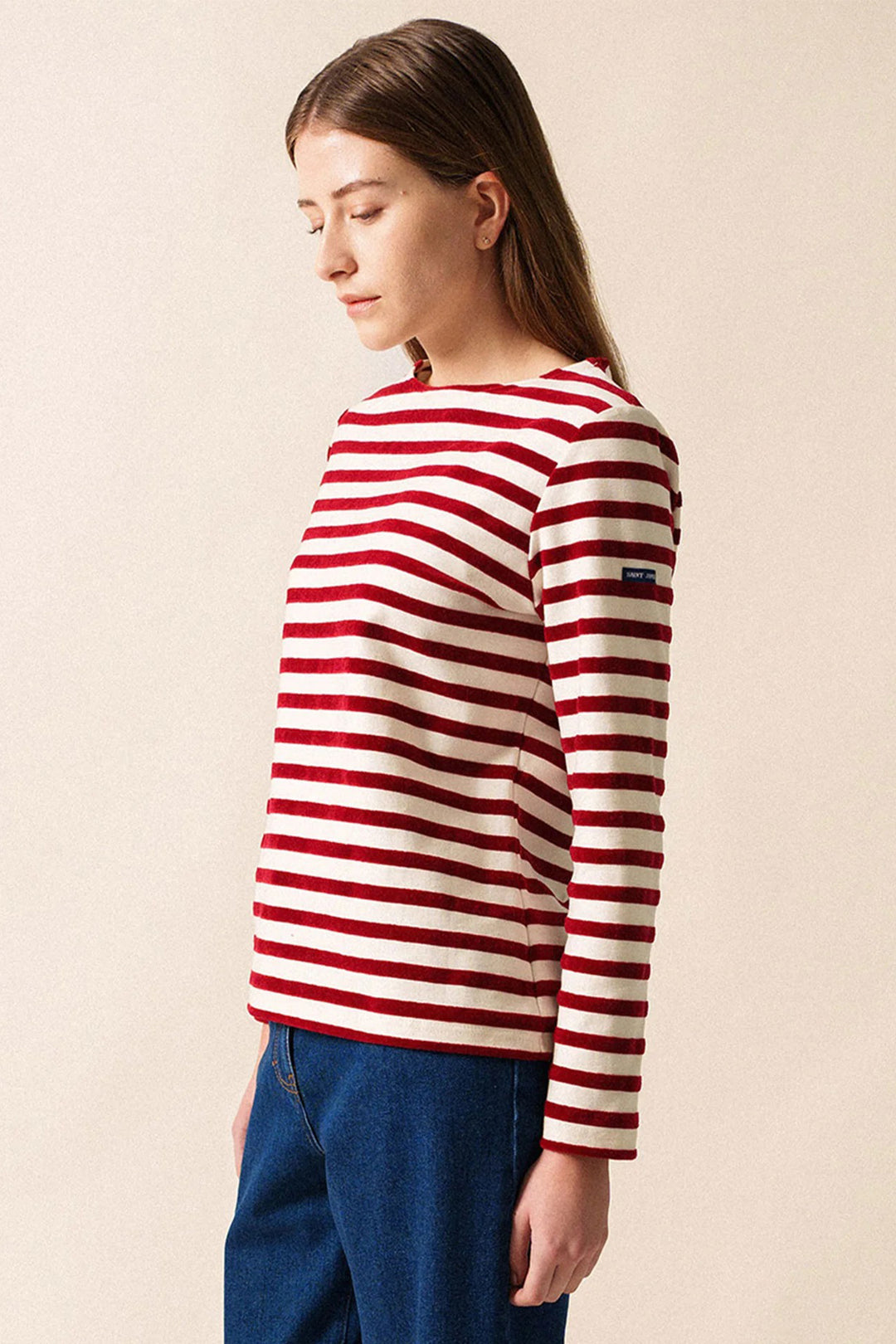 Person wearing a red and white striped sweater against a beige background