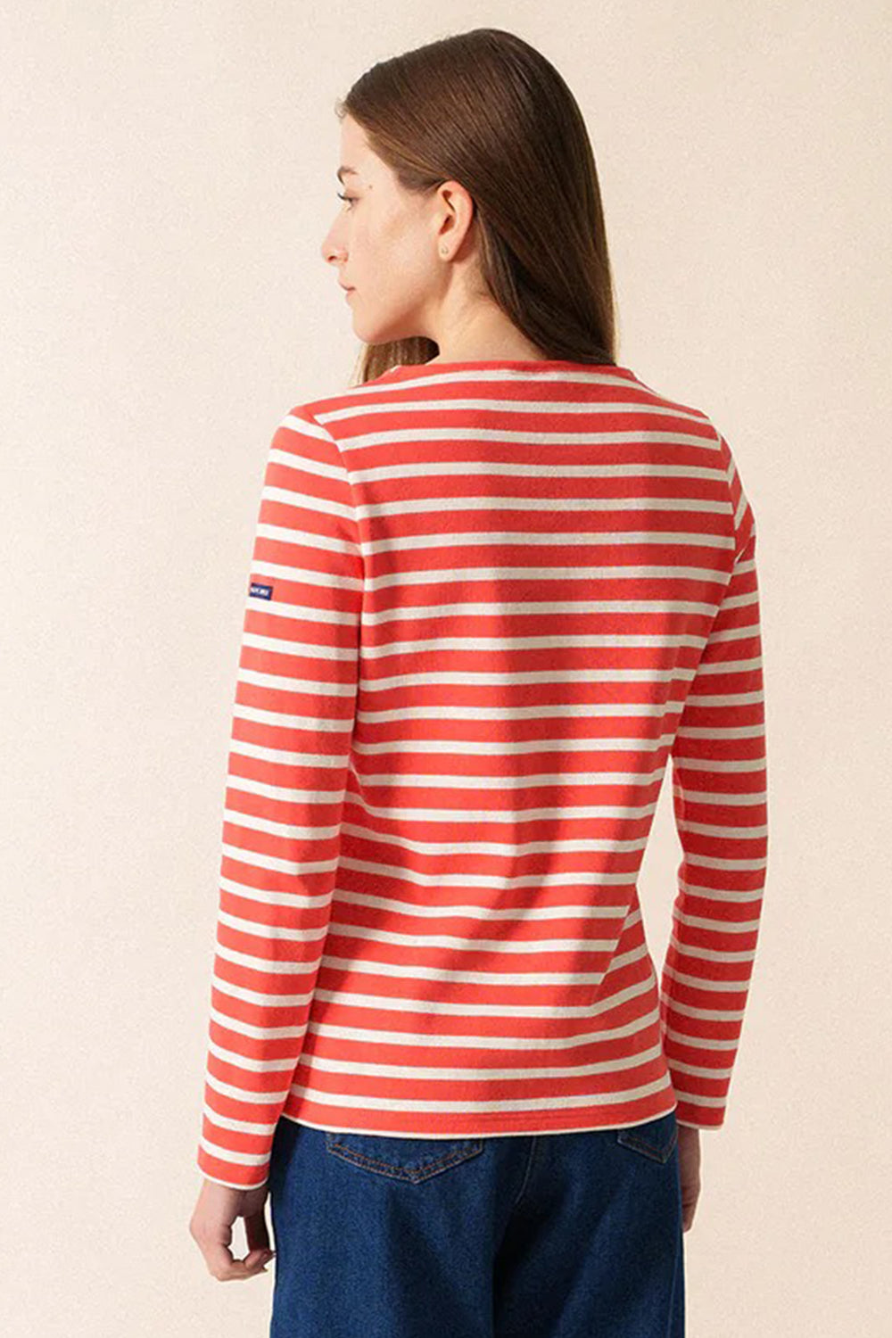 Person wearing a red and white striped long-sleeve shirt on a beige background