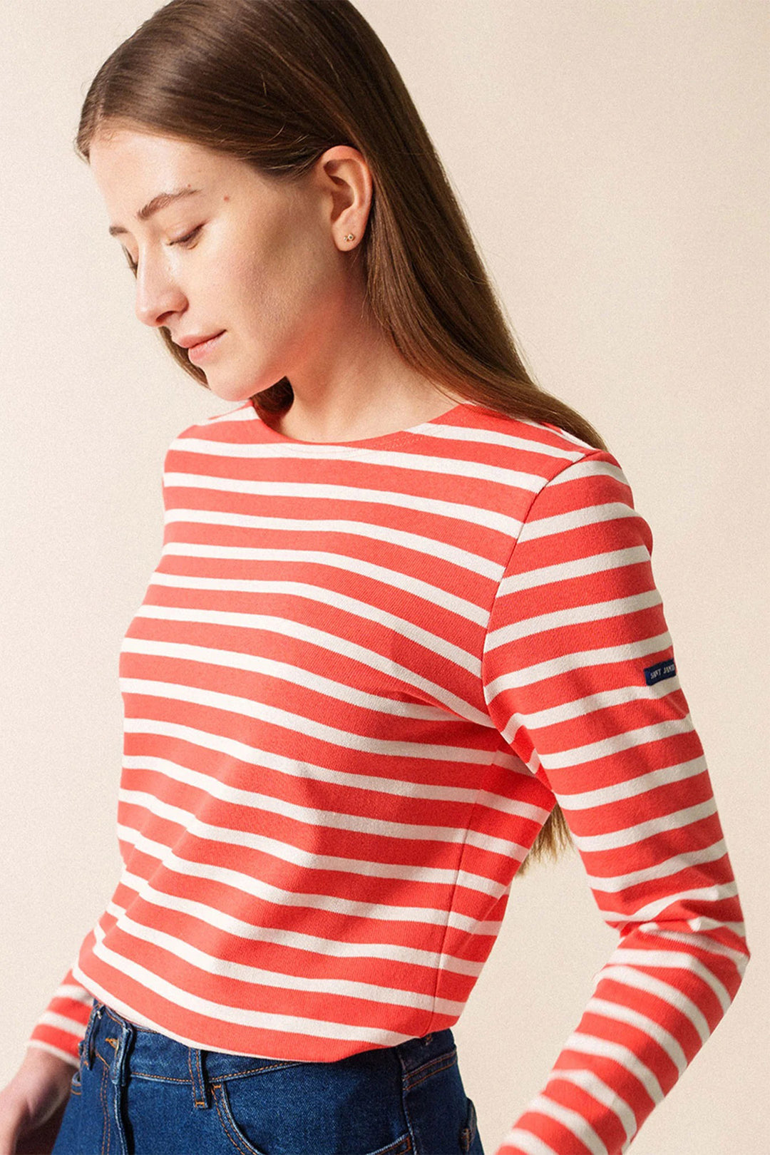 Woman wearing a red and white striped long-sleeve shirt against a beige background