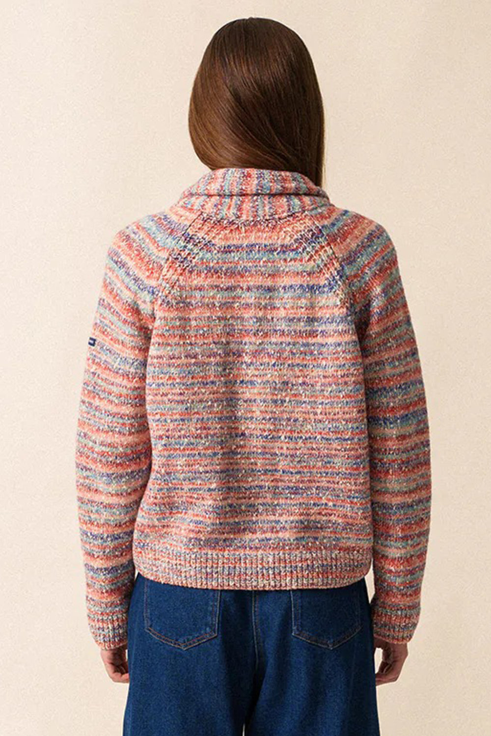 Person wearing a multicolored knit sweater with a neutral background