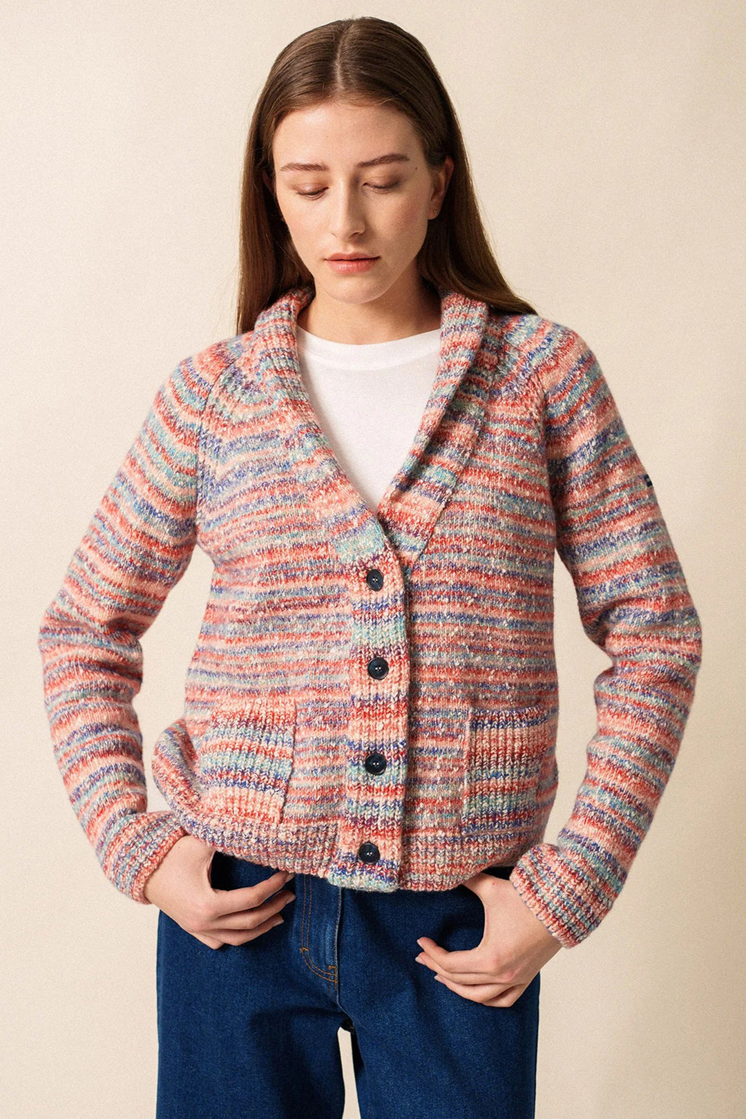 Woman wearing a colorful knitted cardigan against a beige background