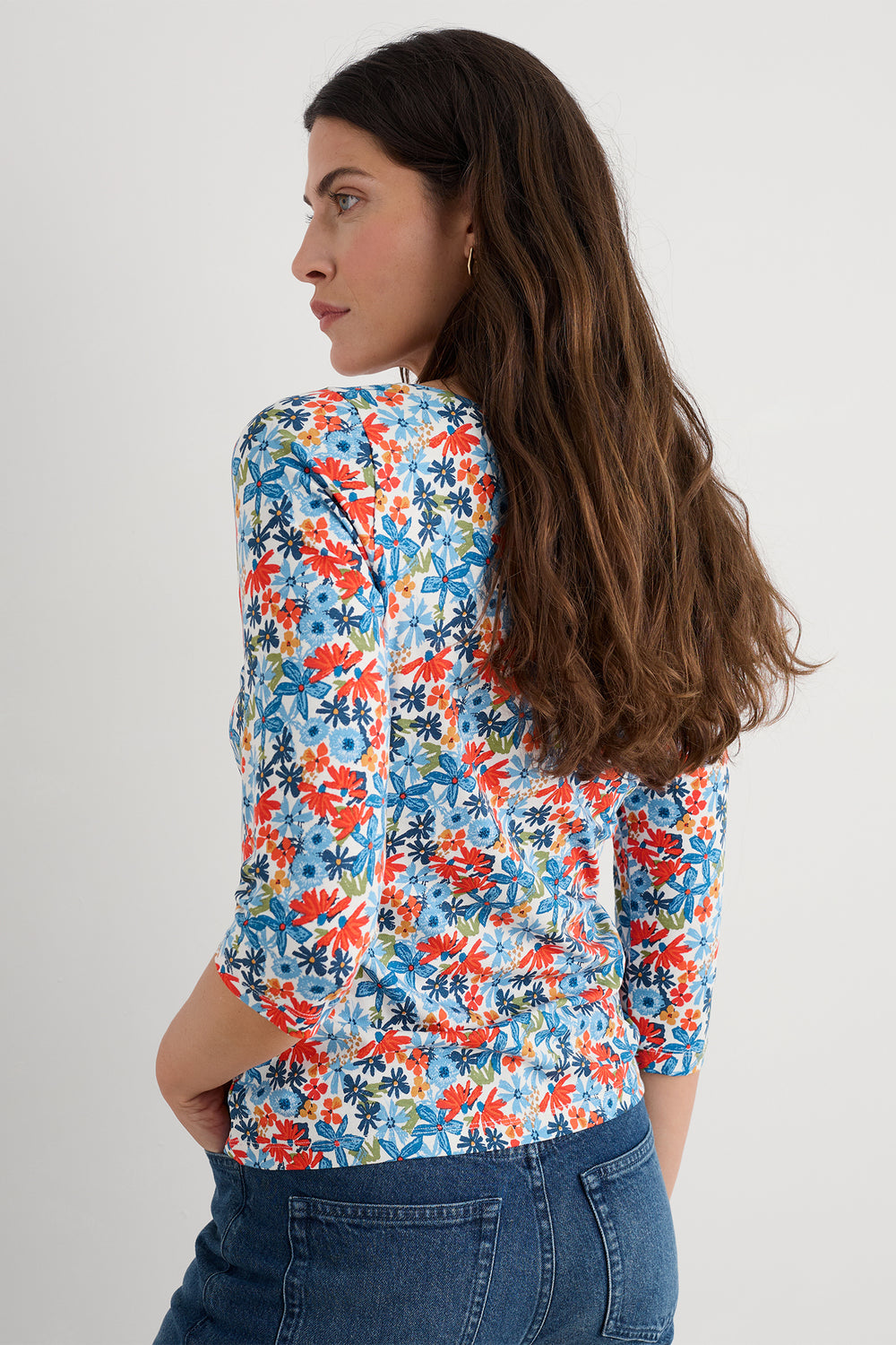 Woman wearing a colorful floral shirt and blue jeans on a white background