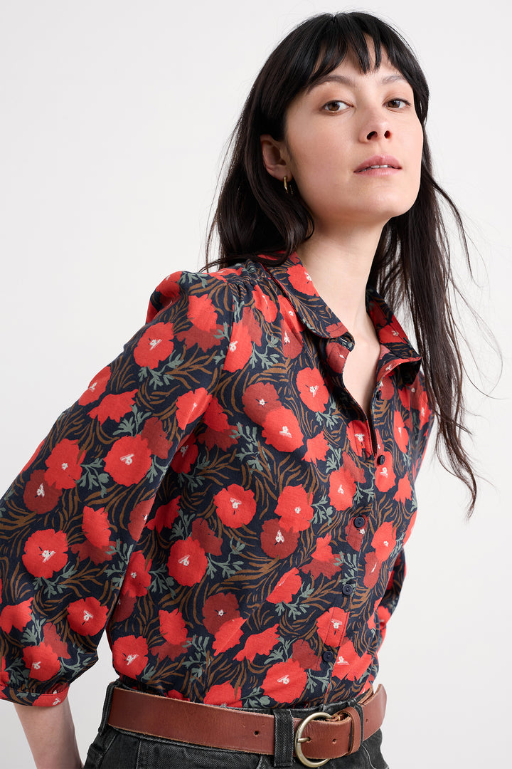 Woman wearing a floral blouse with red flowers on a white background