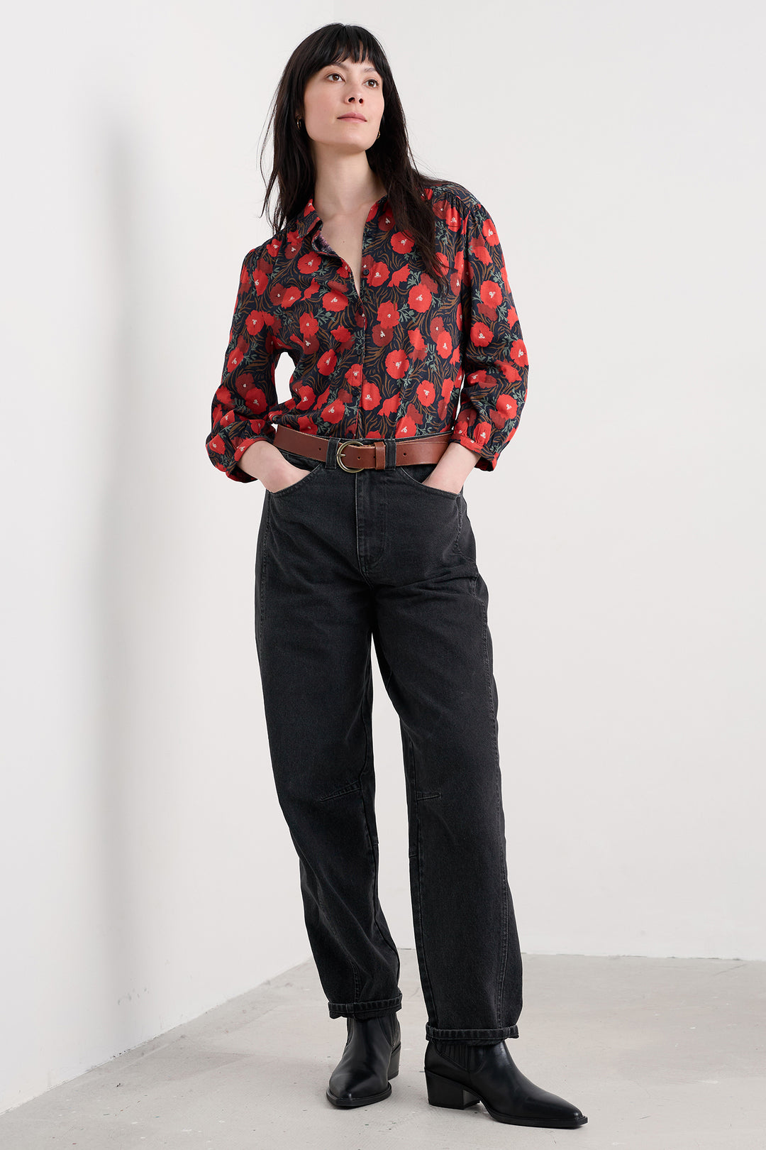 Person wearing a floral jacket and black pants on a white background